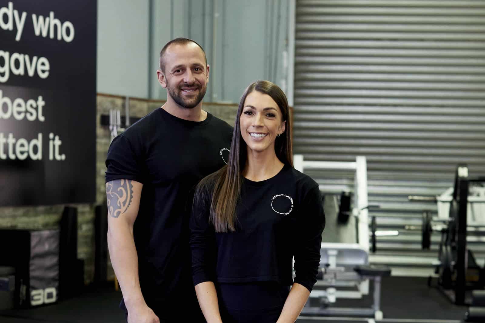 Directors Maeve and Michael standing together in front of some gym equipment
